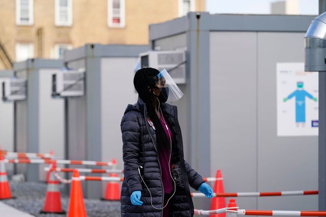 Worker wear a protective face shield walks between portable units set up for registration and testing at a New York City Health + Hospitals COVID-19 testing site in Brooklyn on November 19th, 2020.